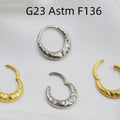 Close-up of a carved concave-convex titanium nose ring in gold finish, showing textured surface.