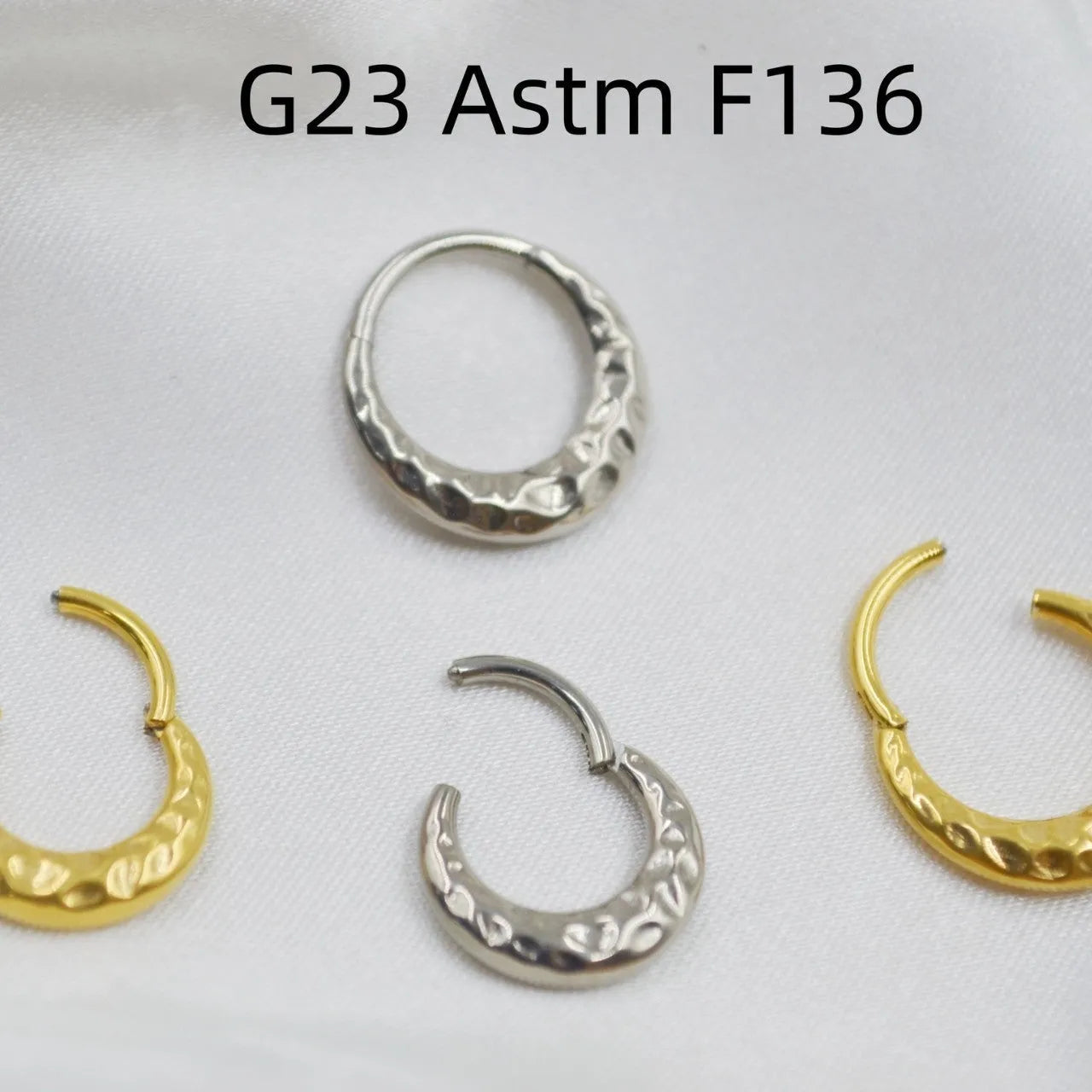 Close-up of a carved concave-convex titanium nose ring in gold finish, showing textured surface.