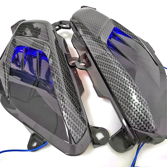 Pair of Yamaha NMAX LED side lamps with carbon fibre design on a blue background.