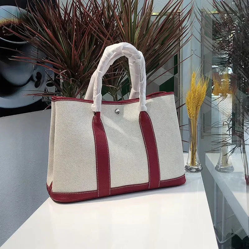 Women's canvas bucket tote bag with leather trim in black, showing internal zipper compartments