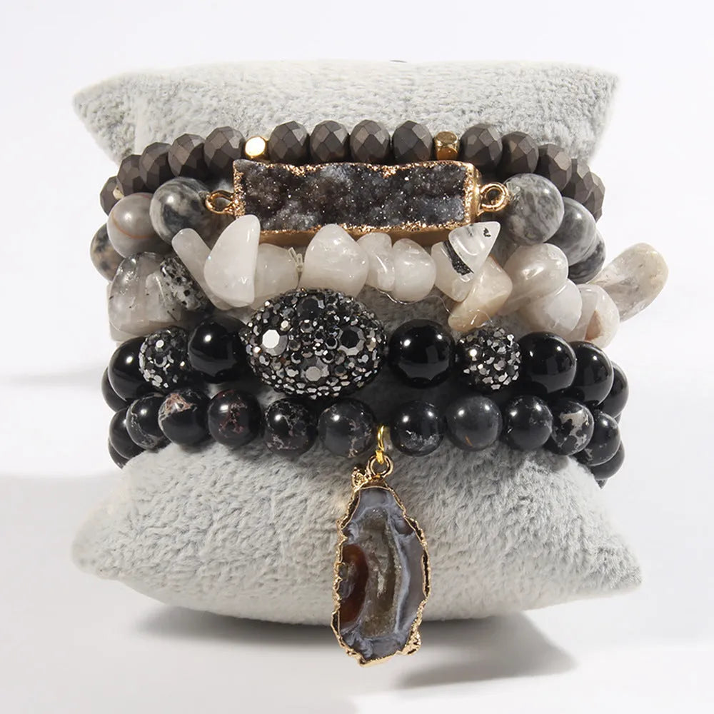 Set of five handmade stretch bracelets with glass, crystal, and hematite beads in irregular shapes on a neutral background