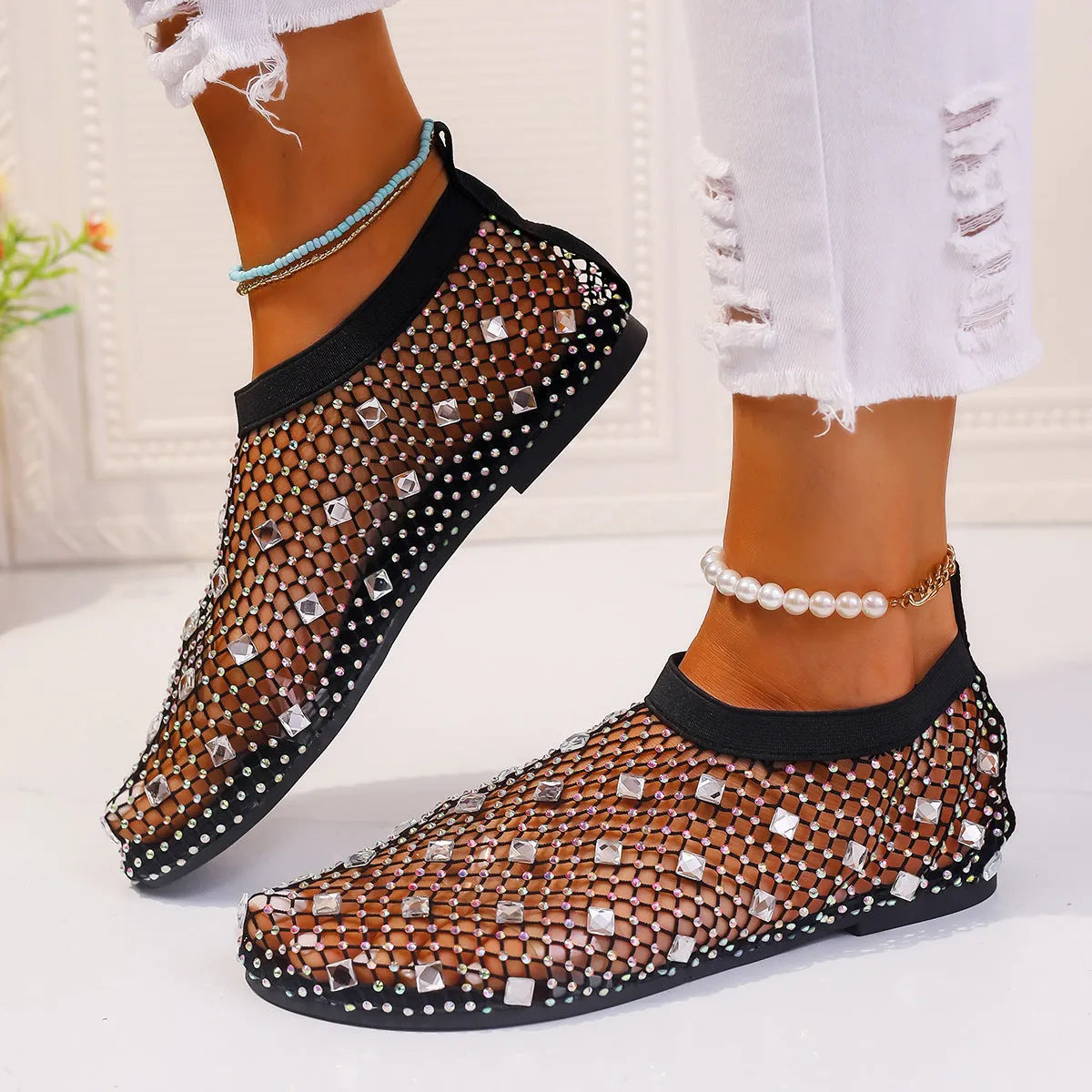 Women's flat sandals with colourful rhinestones on a mesh upper and a rubber sole.