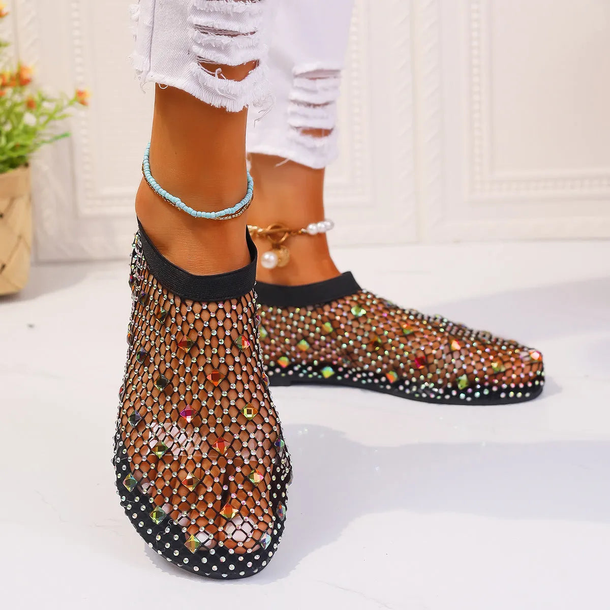 Women's flat sandals with colourful rhinestones on a mesh upper and a rubber sole.