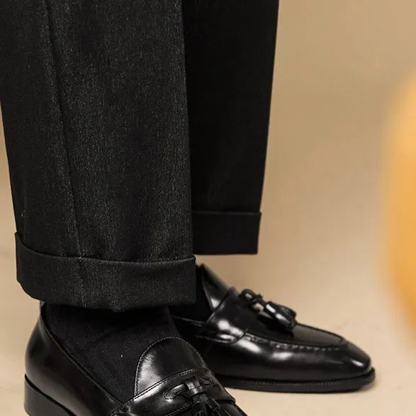 Men's black leather tassel loafers with polished finish and rubber soles for business casual wear