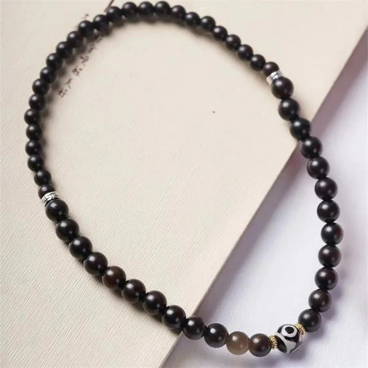 Ebony beaded bracelet with two-circle Tibetan-inspired design on wrist