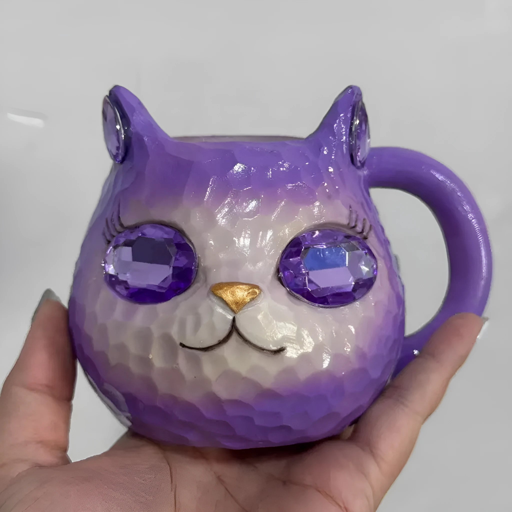 Purple, green, blue, and pink resin cat cup crystal earth craft ornament on display.