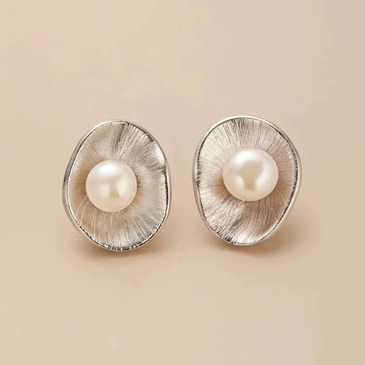 A pair of silver geometric pearl ear studs with gold electroplated finish on needle posts.