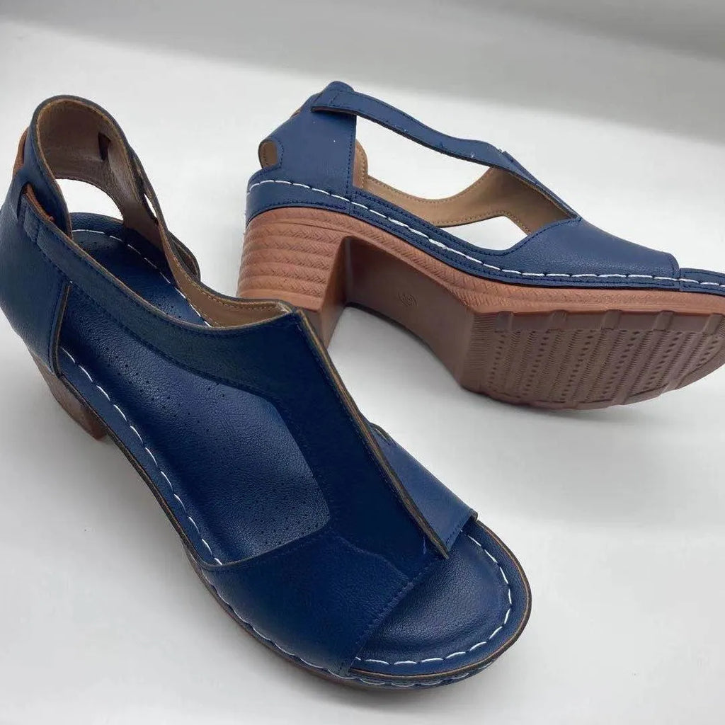 Women's white peep toe wedge sandals with Roman-style buckle ankle straps on a low heel.