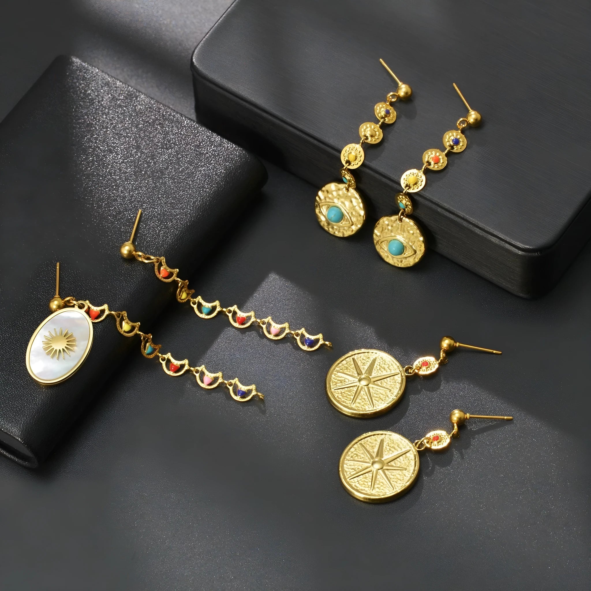 Stainless steel geometric drop earrings showing Eight Awn Star, Eye, and Shell Sun design options.
