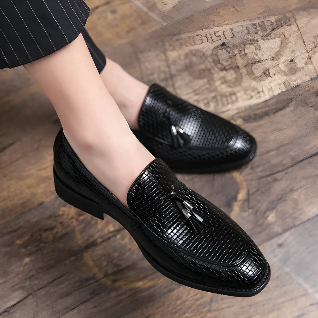 Men's black pointed toe slip-on business shoes with a tassel decoration on the front.
