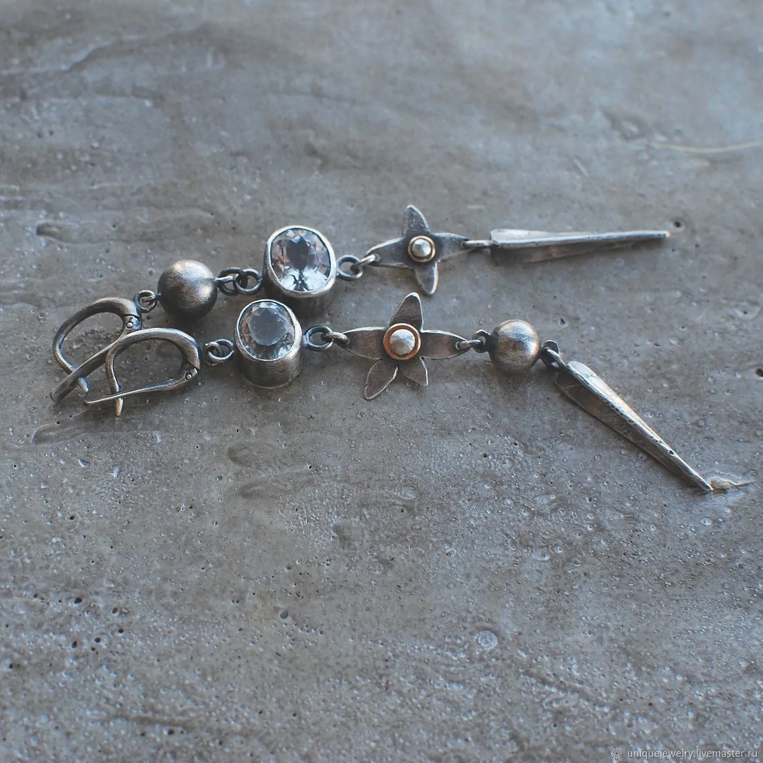 Pair of long geometric pendant earrings in antique silver with rhinestone detail on a white background.