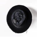 Handmade wool felt skull hat with a pointed conical crown on a neutral background