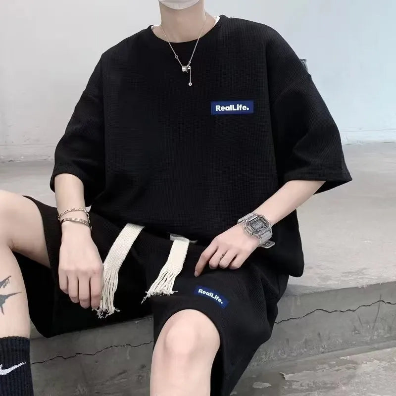 Man wearing a grey waffle-textured cotton blend short sleeve top and matching shorts leisure set.
