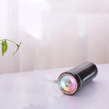 Compact black wireless humidifier with colourful LED lights sitting in car cup holder