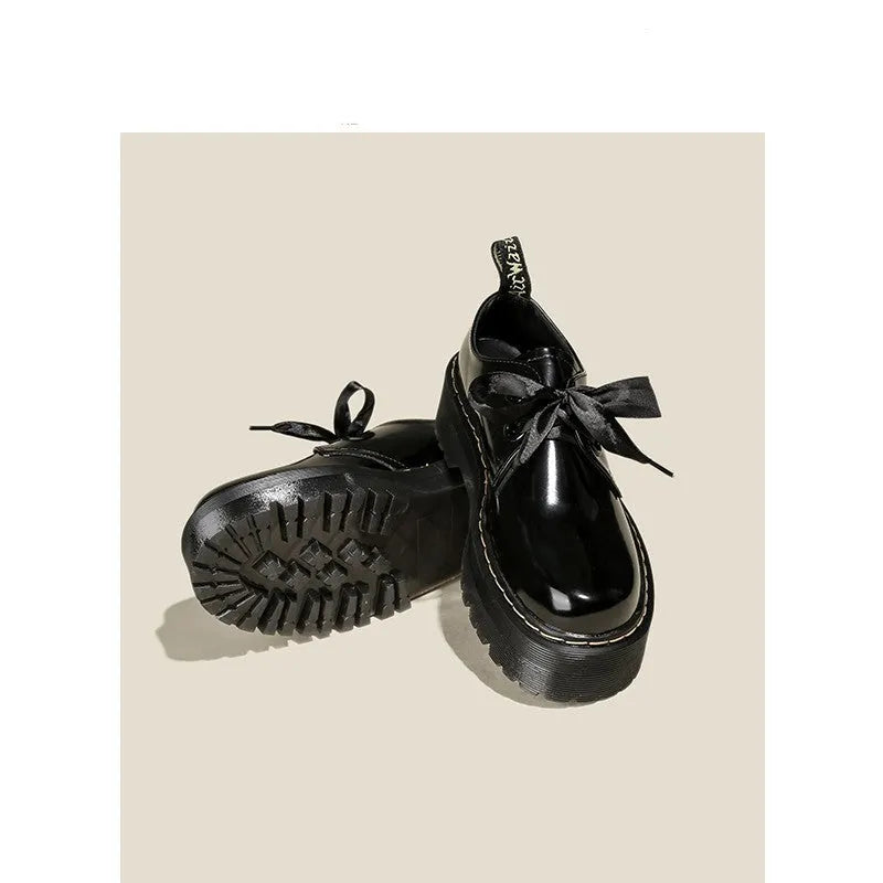 Women's black leather lace-up shoes with thick soles and cross-strap ribbons on the upper.