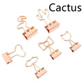 Small gold-plated decorative metal clip with long-tail design, showing optional flamingo, love, clouds, cat, cactus, and bow motifs.