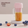 Portable USB mini juicer in avocado green or pink with multiple blade options on a countertop.