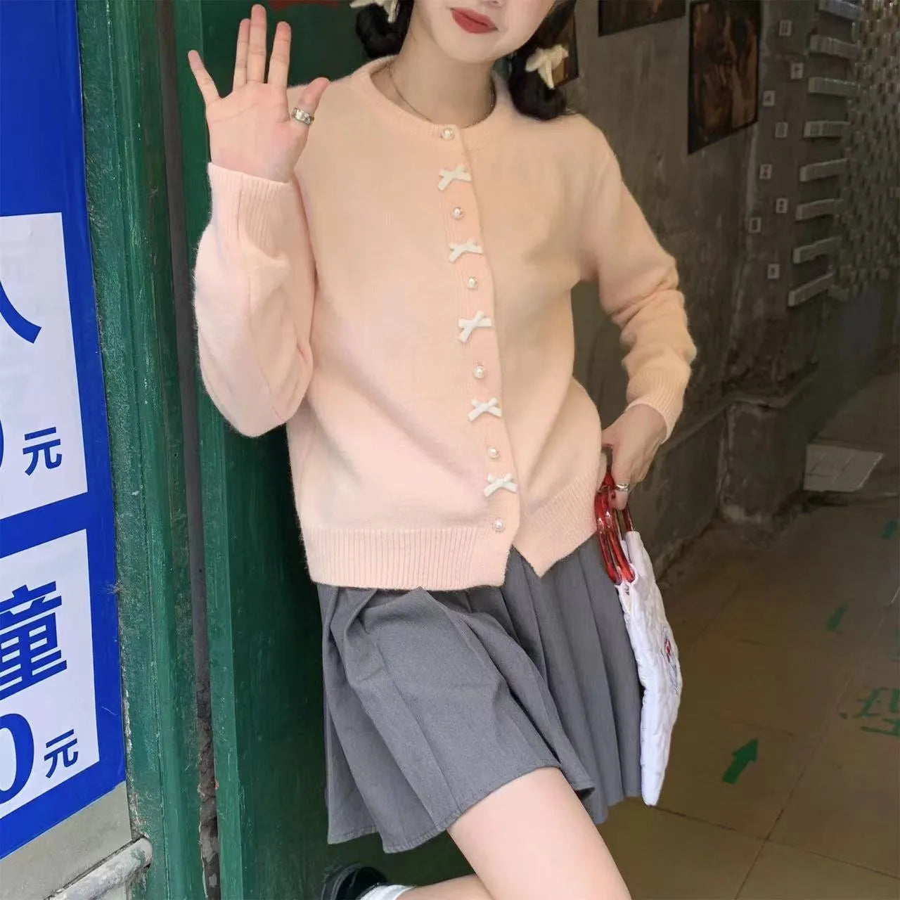 Women's solid colour cardigan sweater with a front bow decoration and pearl buttons.