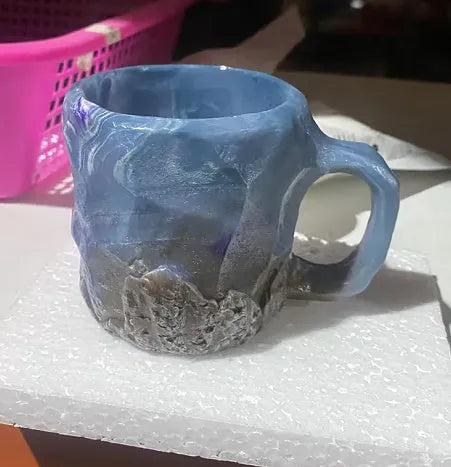 Purple and blue resin coffee mug with crystal texture and handle on wooden table