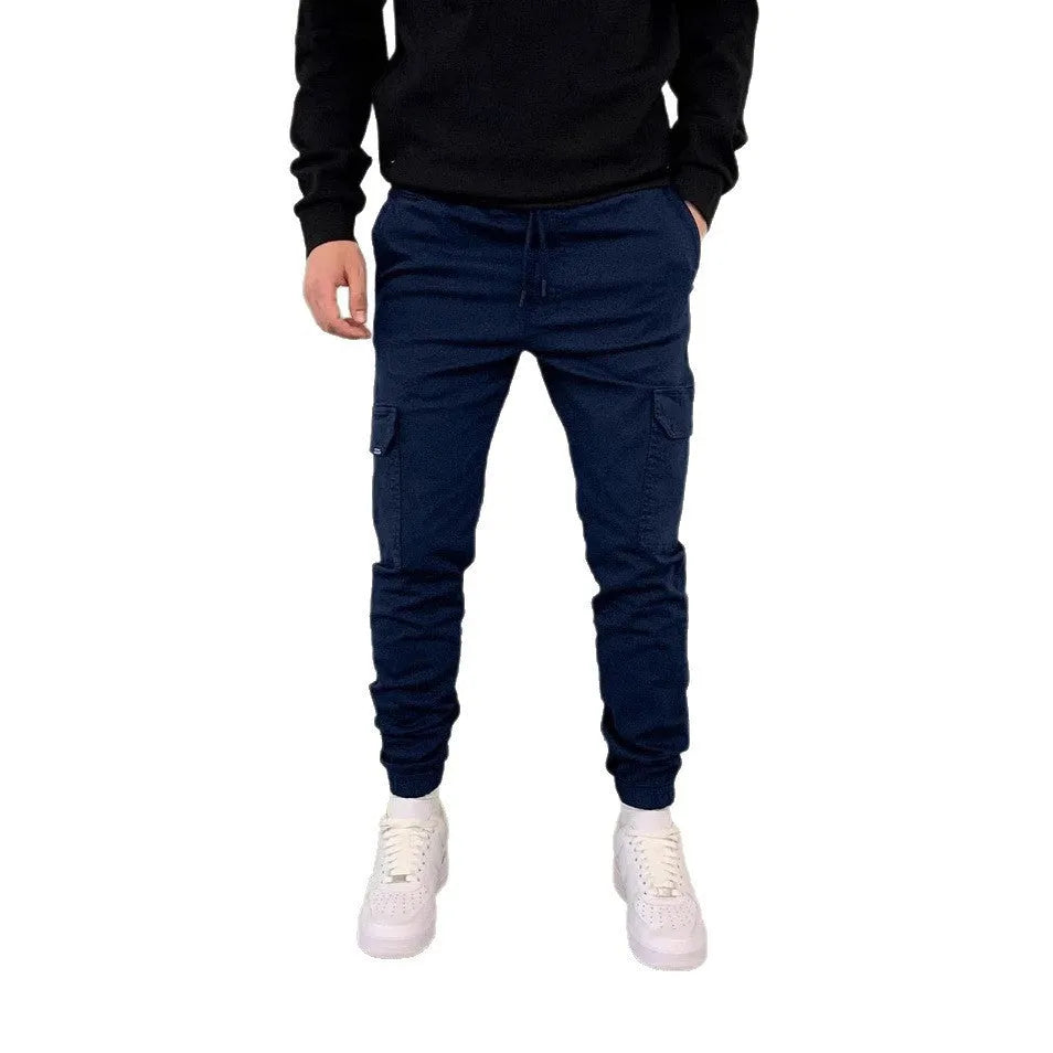 Man wearing loose light blue casual polyester trousers with patch pockets and an elastic waistband.