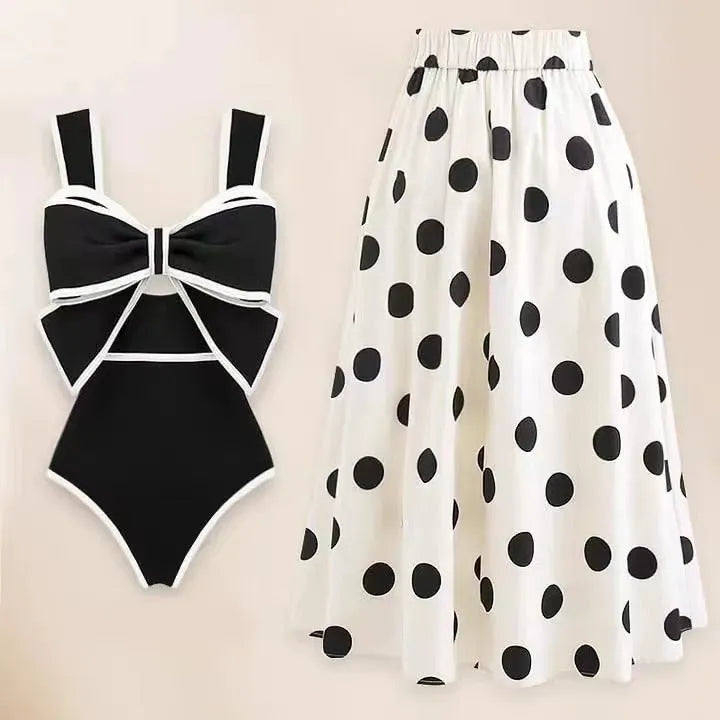 Women's black one-piece swimsuit with attached white skirt-style beach dress and a bow detail.