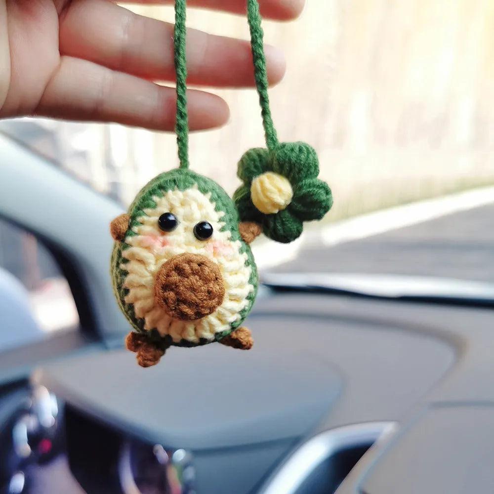 Handmade crocheted wool car pendant with a cartoon flower in avocado, pink rainbow, or red rainbow colours.