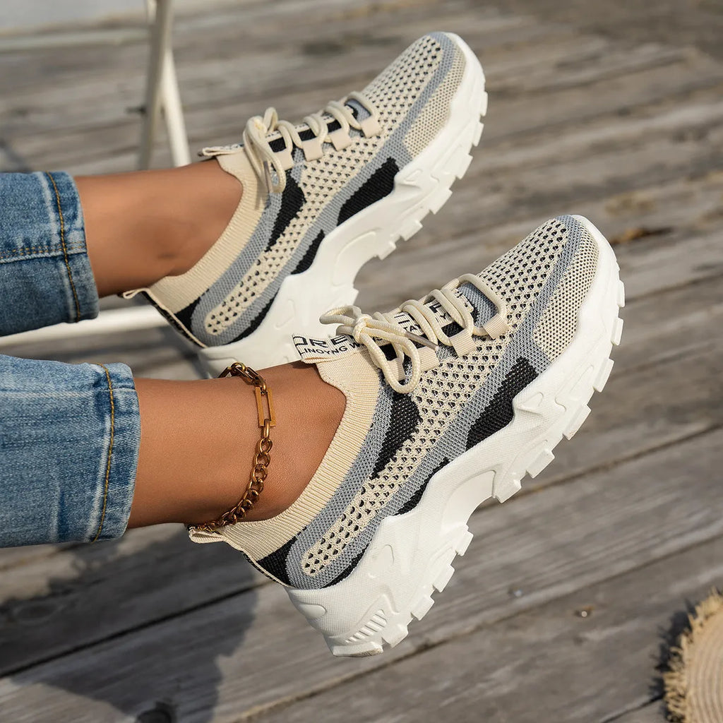 Women's Flyknit mesh lace-up sneakers in a grey colourway showing round toe and low profile.