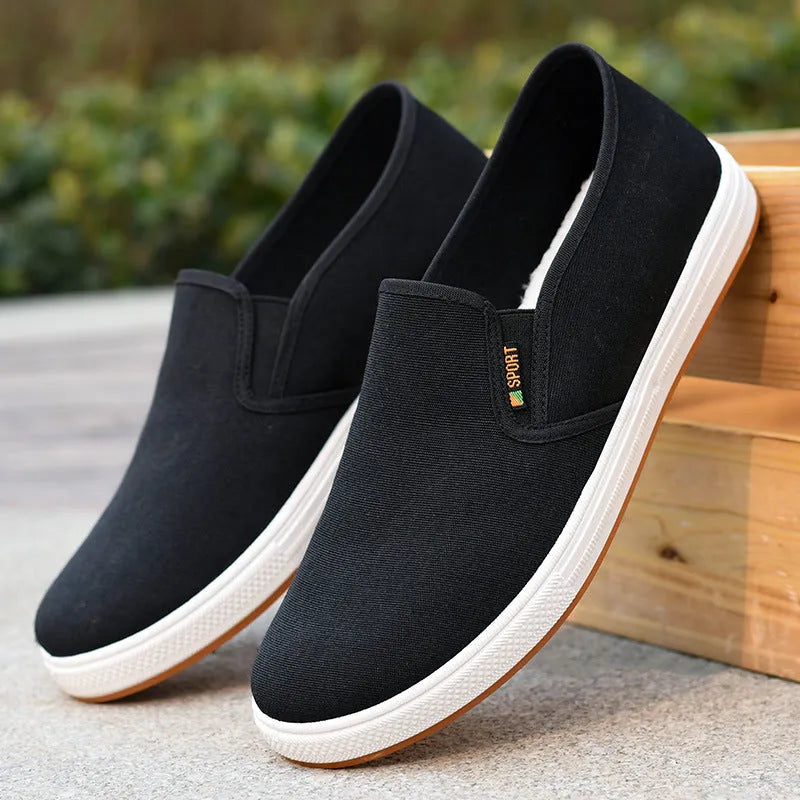 Men's black low-top canvas slip-on shoes with round toe and shallow mouth design on a white background.
