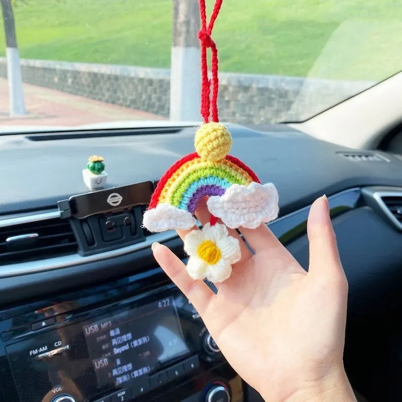 Handmade crocheted wool car pendant with a cartoon flower in avocado, pink rainbow, or red rainbow colours.