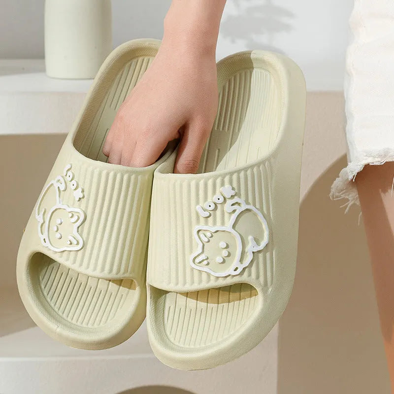 Green cat slippers with a thick EVA platform and non-slip sole on a wooden floor.