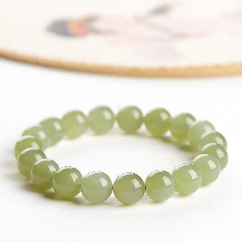 Polished Hetian jade ball bracelet on wrist, showing clear beads.