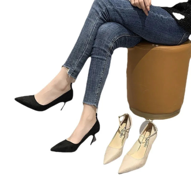 Black and creamy white women's stiletto heel pumps with a metal buckle detail on the upper.