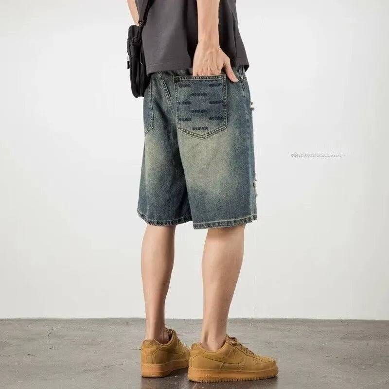 Man wearing blue retro loose-hole denim shorts with a straight leg cut on a casual background.