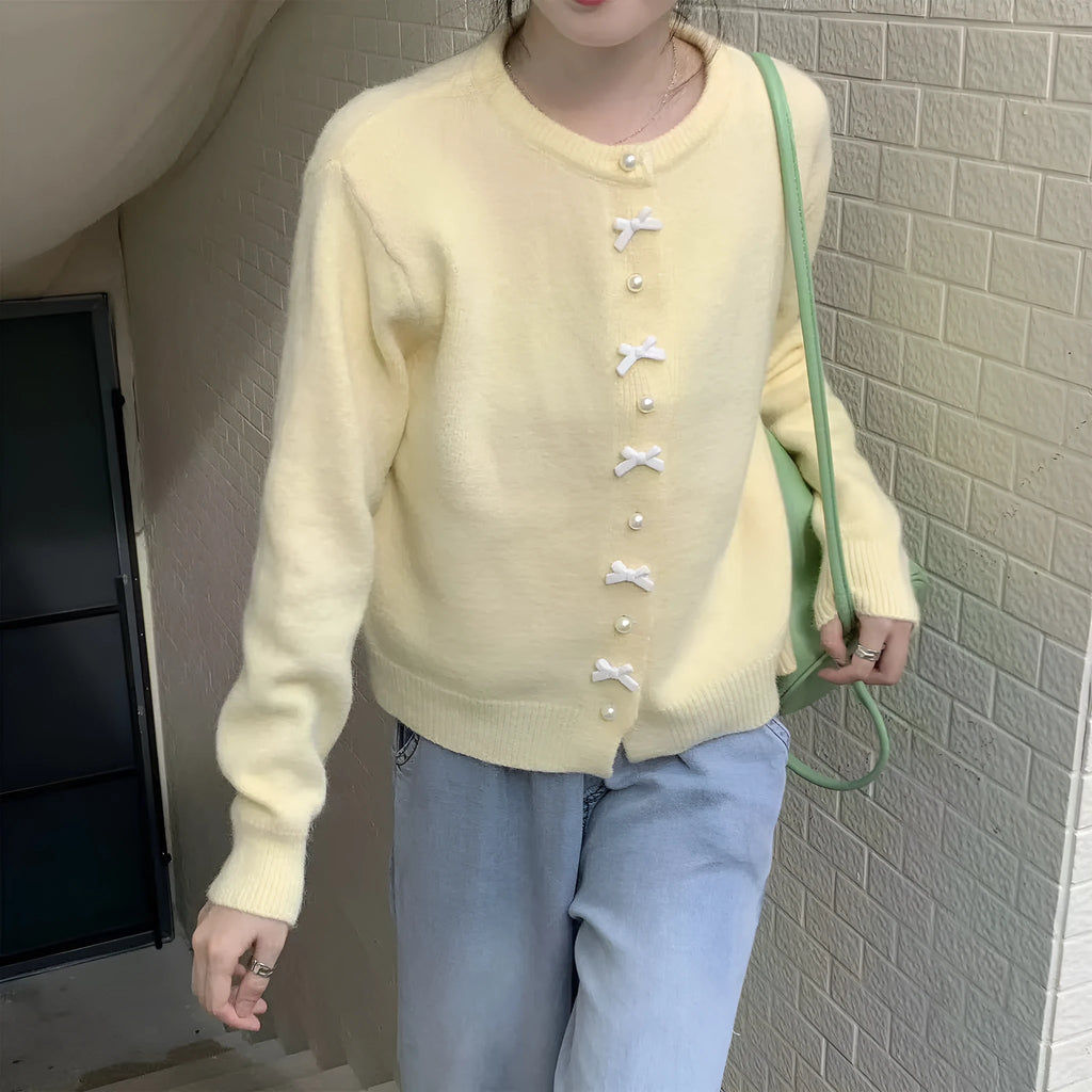 Women's solid colour cardigan sweater with a front bow decoration and pearl buttons.