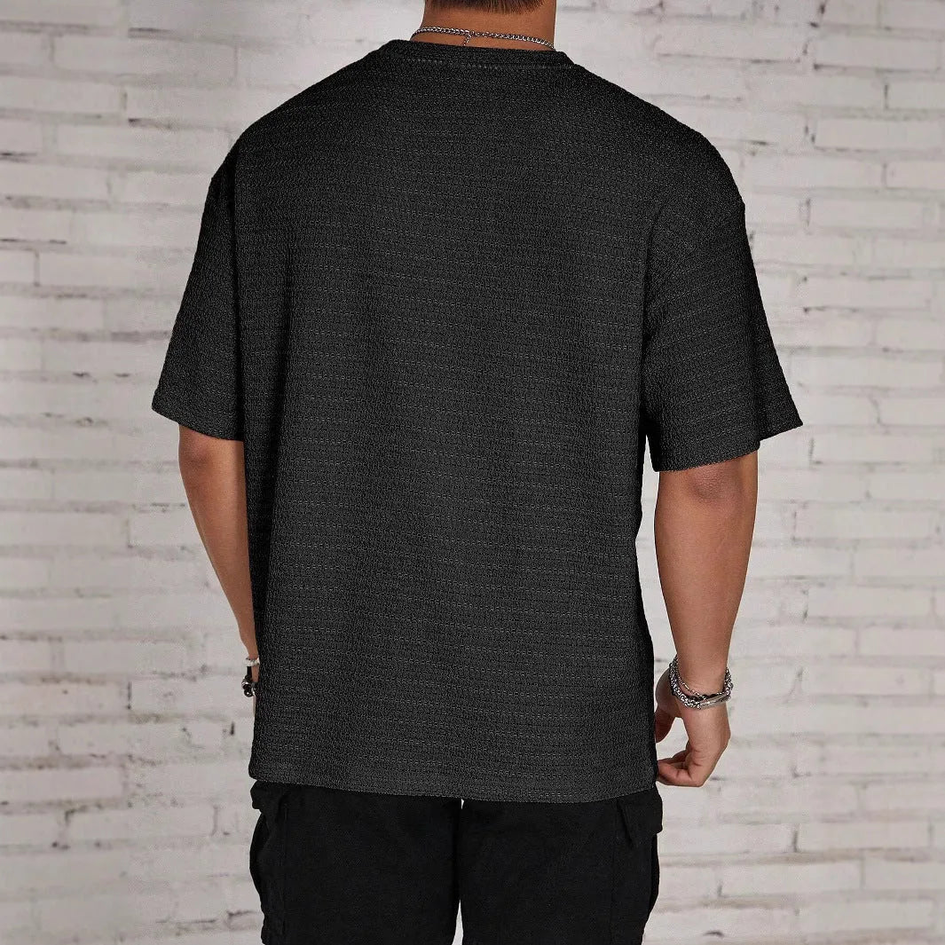 Man wearing a slim fit black round neck T-shirt with a loose hollow knit texture.