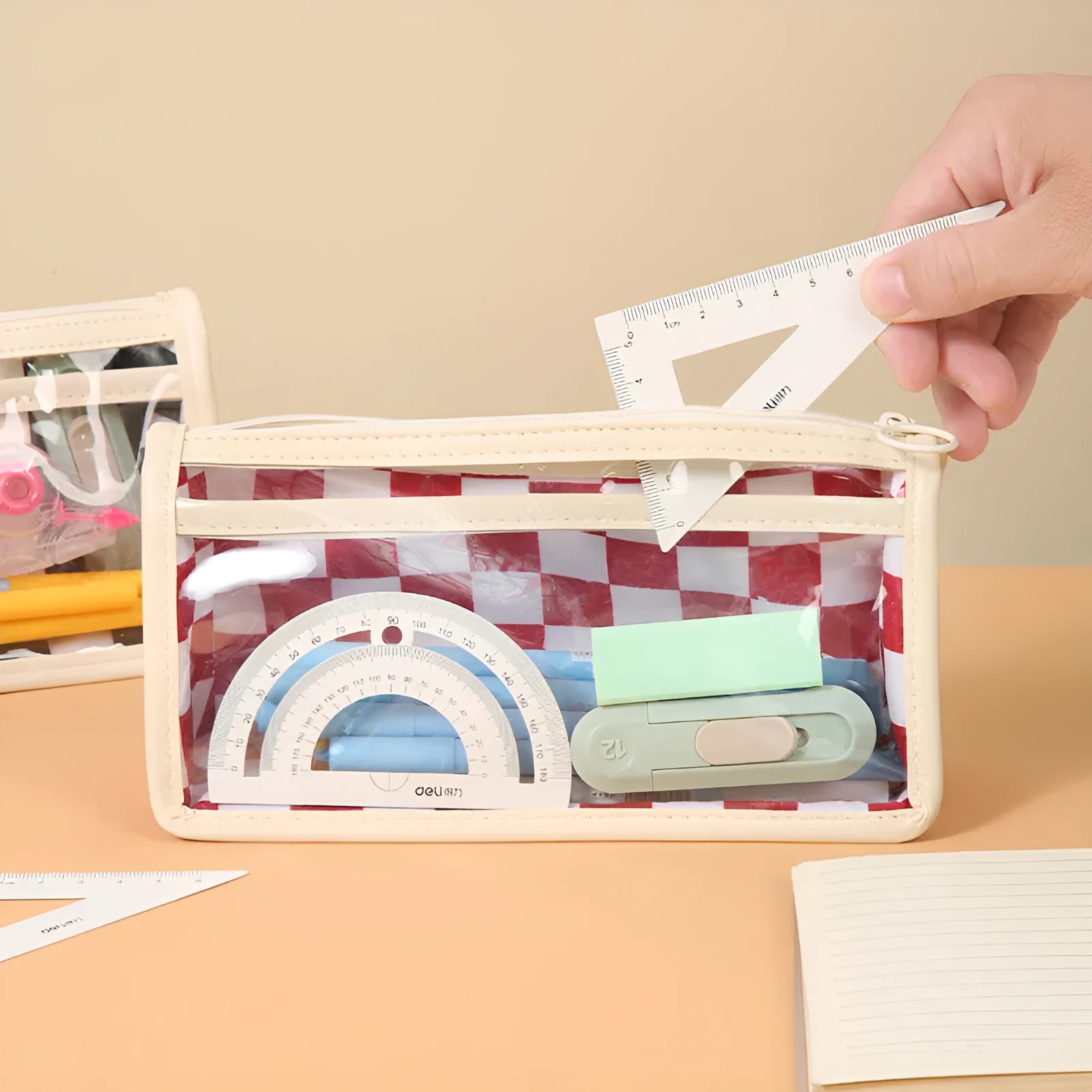 Large transparent PVC pencil case with a black and white chessboard grid pattern, showing pens inside.