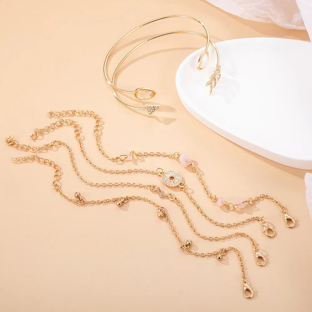 Gold-coloured zinc alloy bracelet set with six charms including arrow, water drop, V, and spot drill designs.