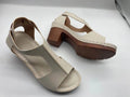 Women's white peep toe wedge sandals with Roman-style buckle ankle straps on a low heel.