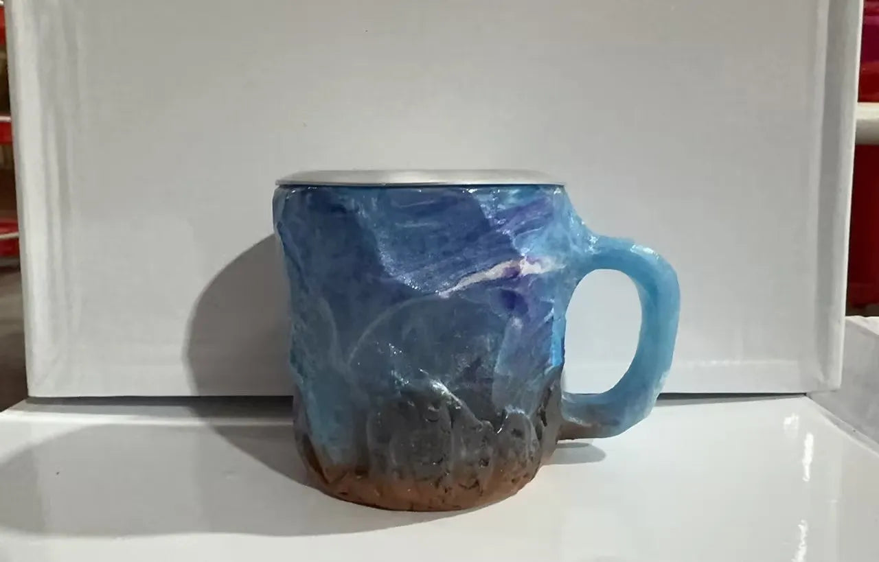 Purple and blue resin coffee mug with crystal texture and handle on wooden table