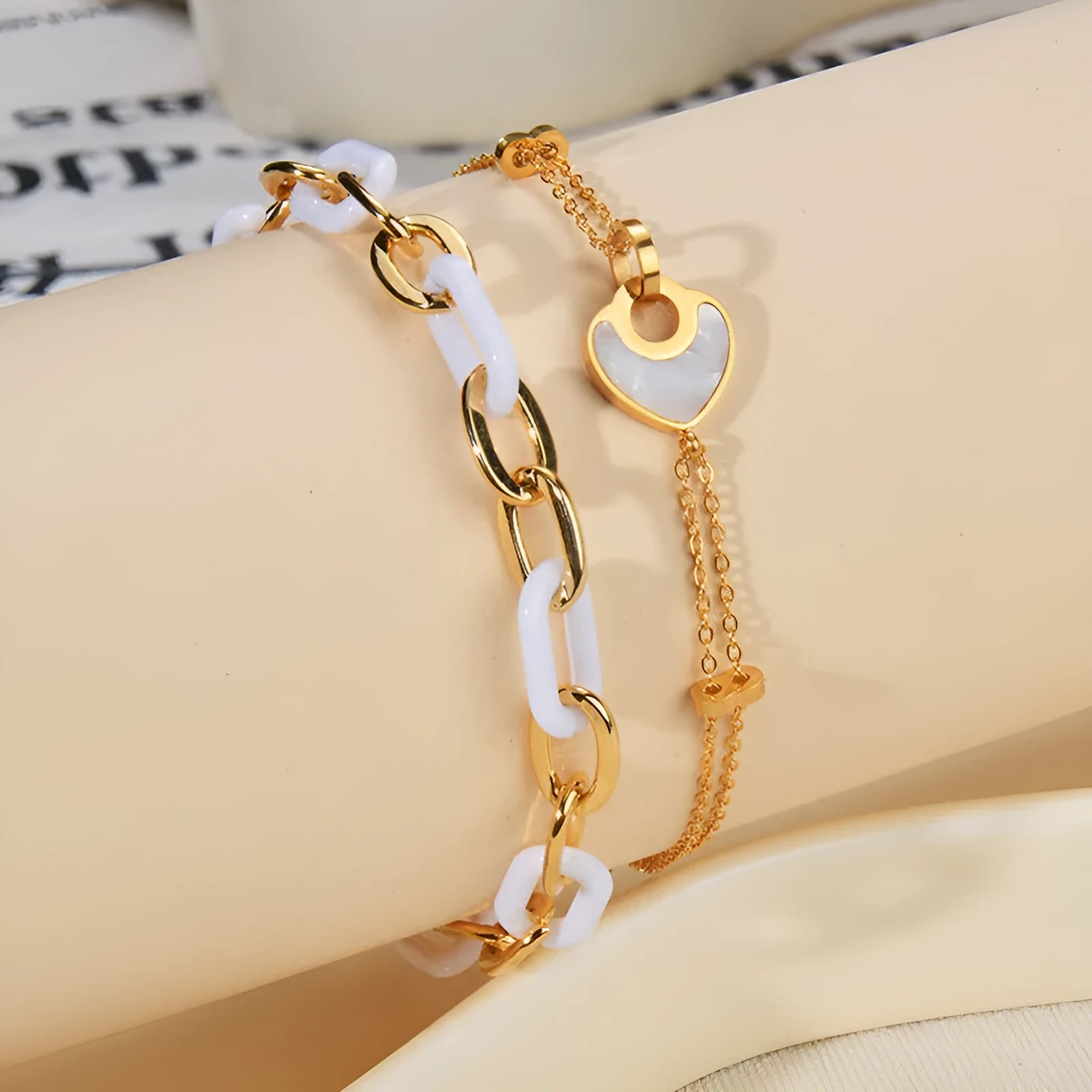 Women's stainless steel bracelet with double-layer design and a hanging heart charm in a resin-like electroplated finish.
