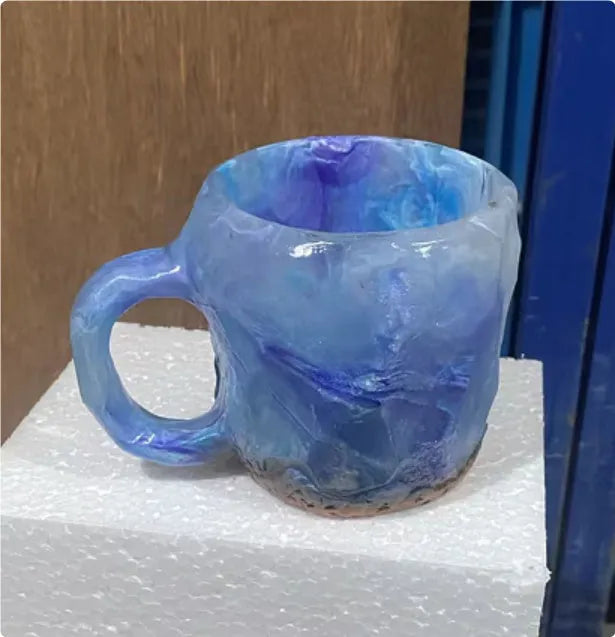Purple and blue resin coffee mug with crystal texture and handle on wooden table