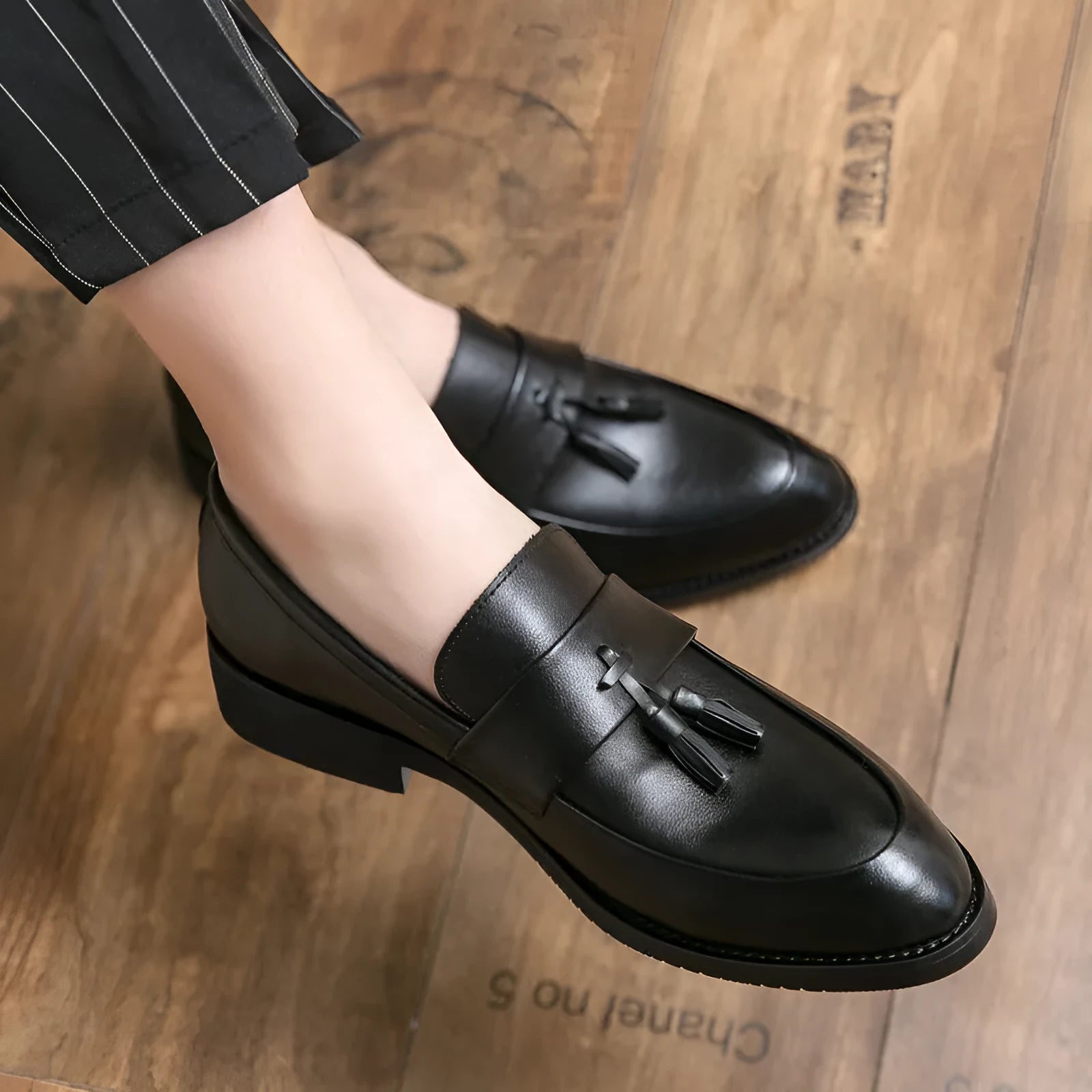 Men's black and brown tassel loafers with a slip-on design and rubber sole for business casual wear.