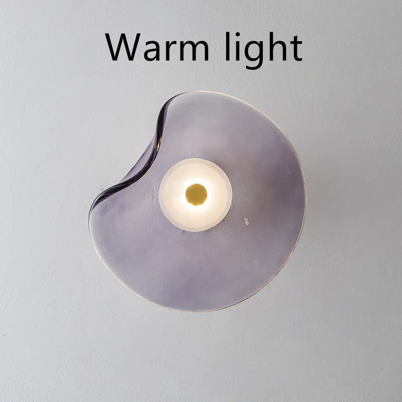 Round decorative wall lamp with glass shade in choice of cognac, light purple, or smoky grey finishes for bedroom lighting