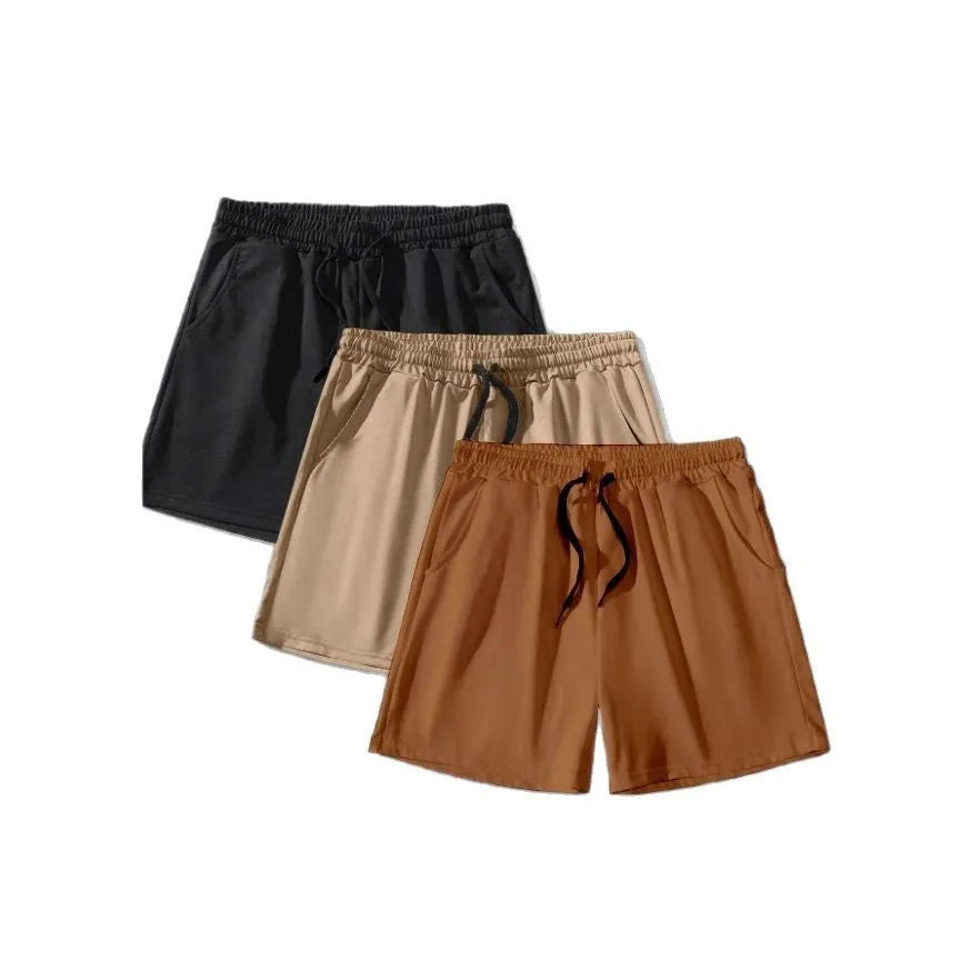 Set of three solid colour men's drawstring shorts in black, khaki, and light brown laid flat.