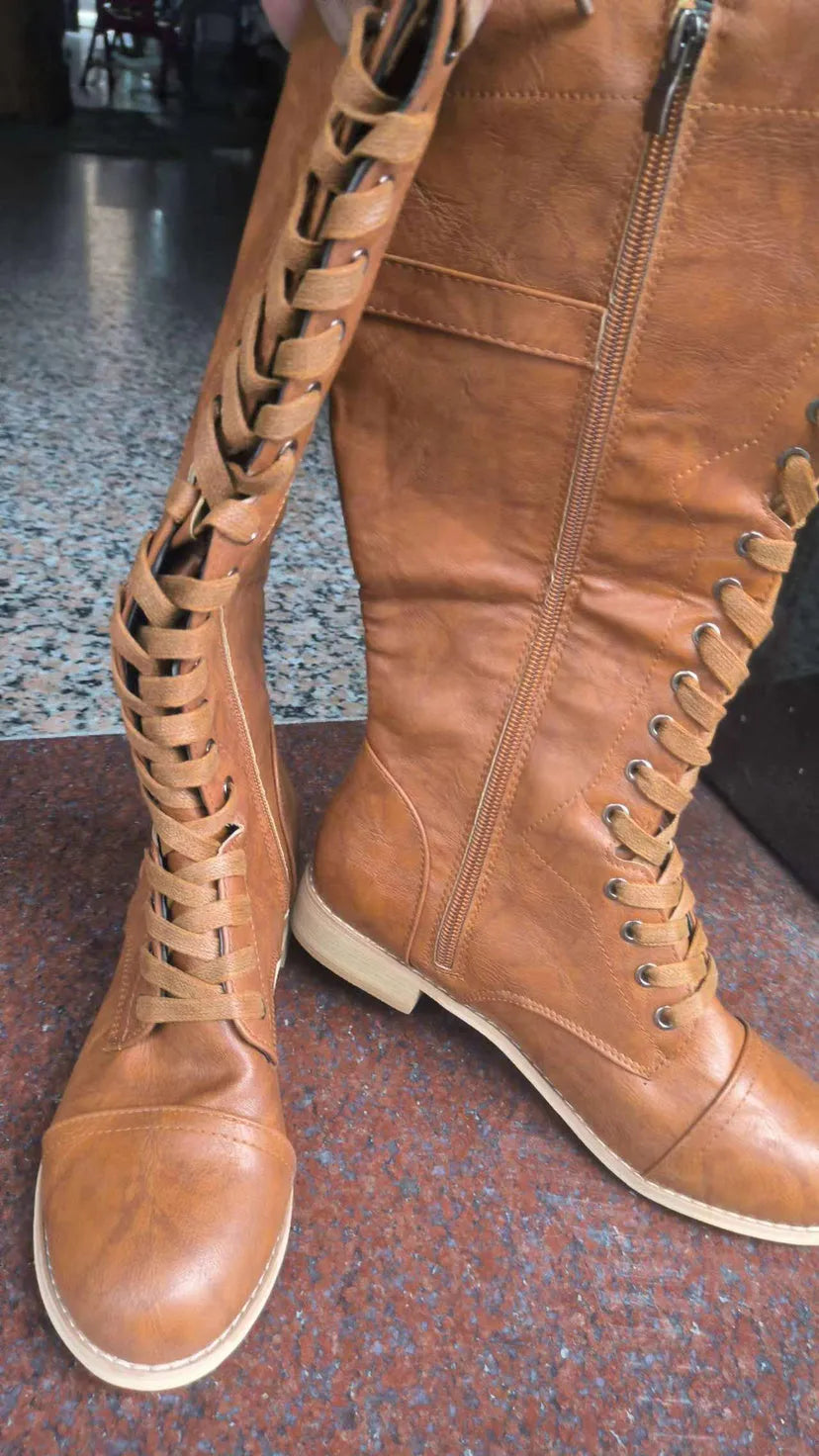 Women's brown ankle boots with a front cross strap and buckle fastening, shown on a white background.
