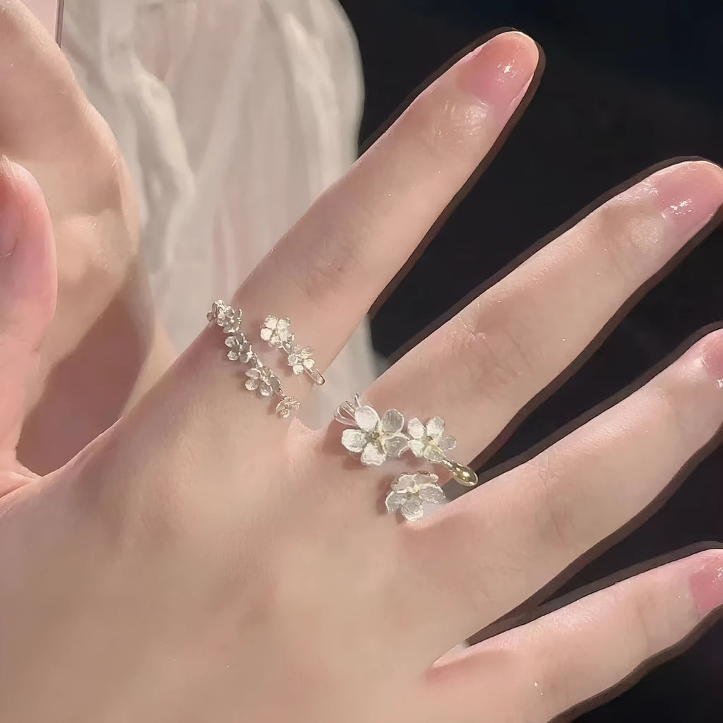 Open silver-tone ring with a 3D jasmine flower and multiple small flowers on the band.