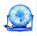 Small black USB desk fan with adjustable angle on wooden desk next to laptop