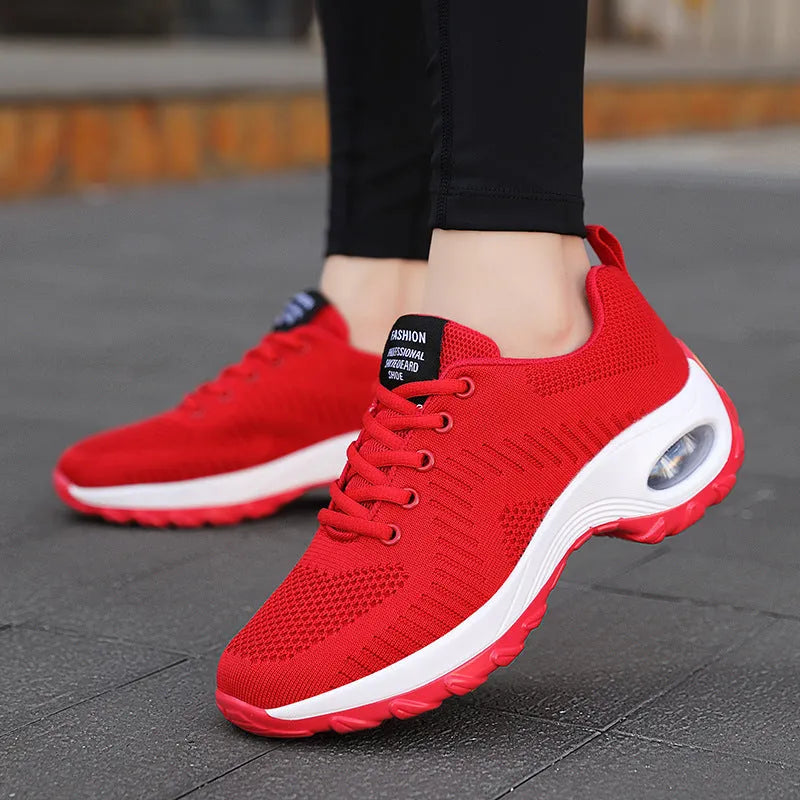 Women's red and black round toe lace-up mesh sneakers with low top and flat mid heel.