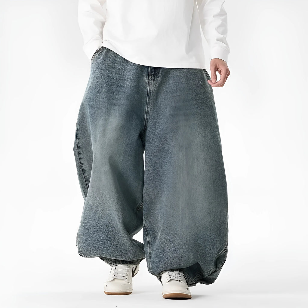 Men's plus-size baggy blue jeans with a wide leg and straight hem on a casual background.