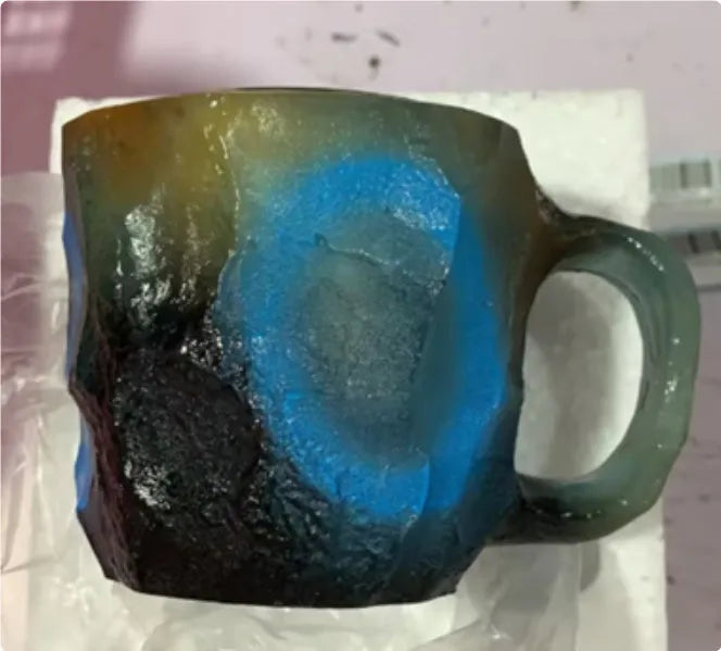Purple and blue resin coffee mug with crystal texture and handle on wooden table